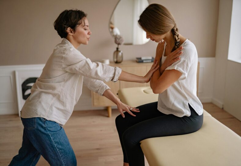 A therapist assisting a patient during a therapeutic session indoors, focusing on wellness and care.